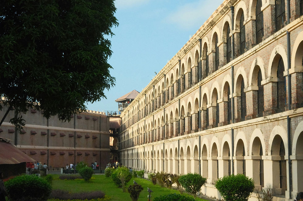 Historic building with arched windows, surrounded by green lawns and trees. Blue sky in the background, creating a serene atmosphere.