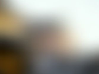 Yellow bus on city street with cyclists and cars. Historic brick building in the background. Traffic lights and evening light create a calm mood.