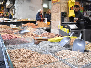 "Metal bins overflowing with fresh nuts, sunflower seeds, and dried snacks at a traditional stall in Machane Yehuda Market, Jerusalem."