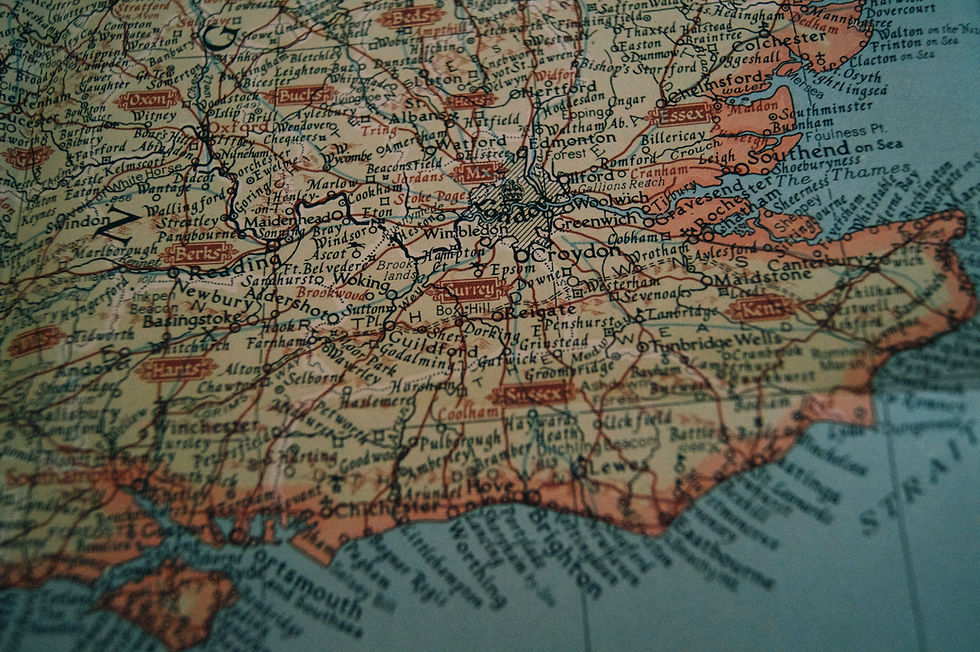 Close-up of a vintage map depicting southern England. The map features names of towns and regions like Surrey and Kent, with muted colors.