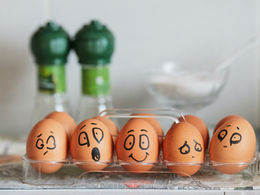 A carton of eggs with faces of various emotions drawn on them. 