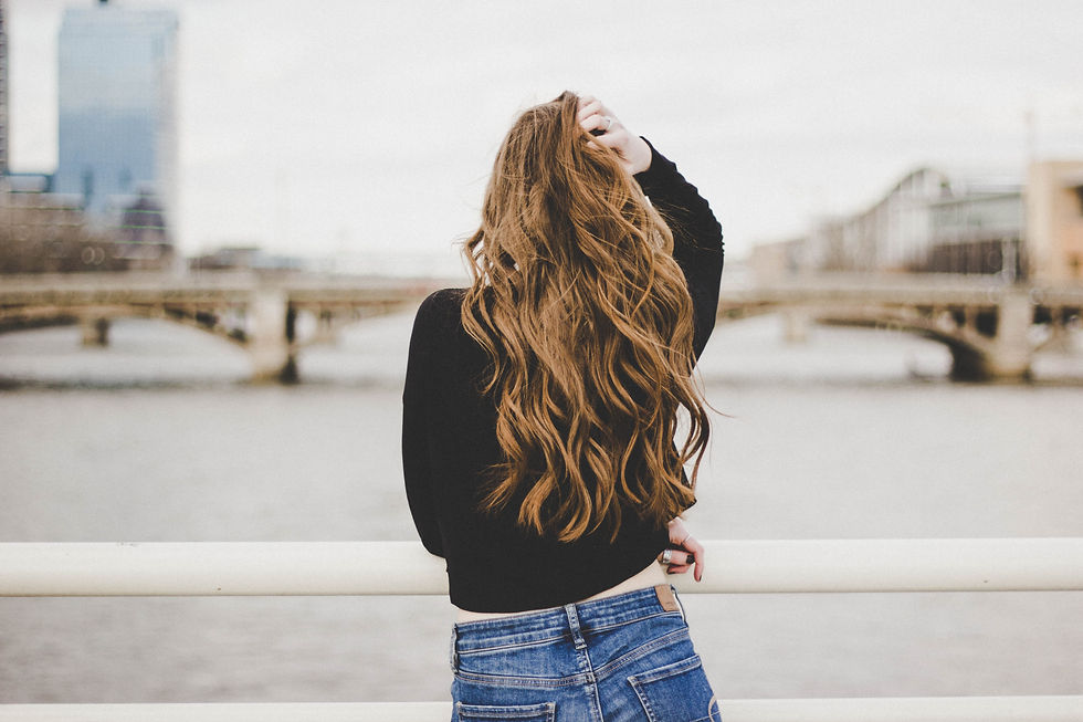 Woman model outside from behind, with long flowing red hair