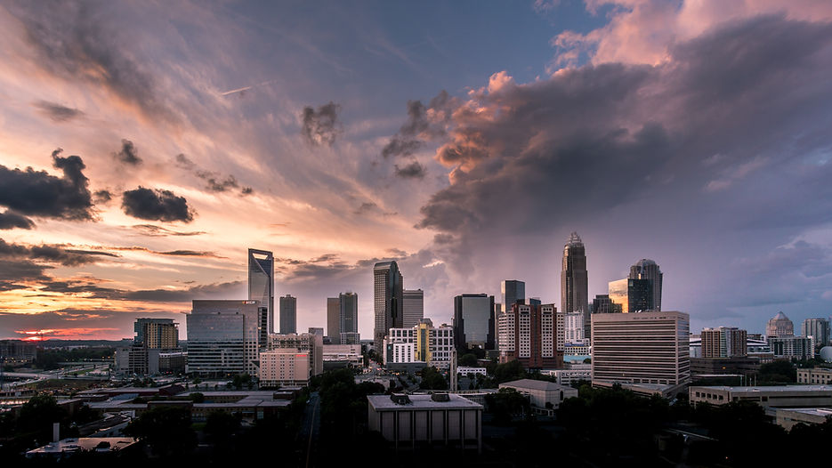 charlotte skyline at dusk with some clouds and sunset peaking through.