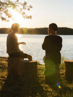 two people having a conversation beside a lake