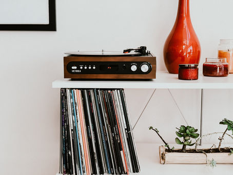 Vintage vibes fill the room with a classic record player and a neatly arranged vinyl collection, complemented by stylish red and green accents.