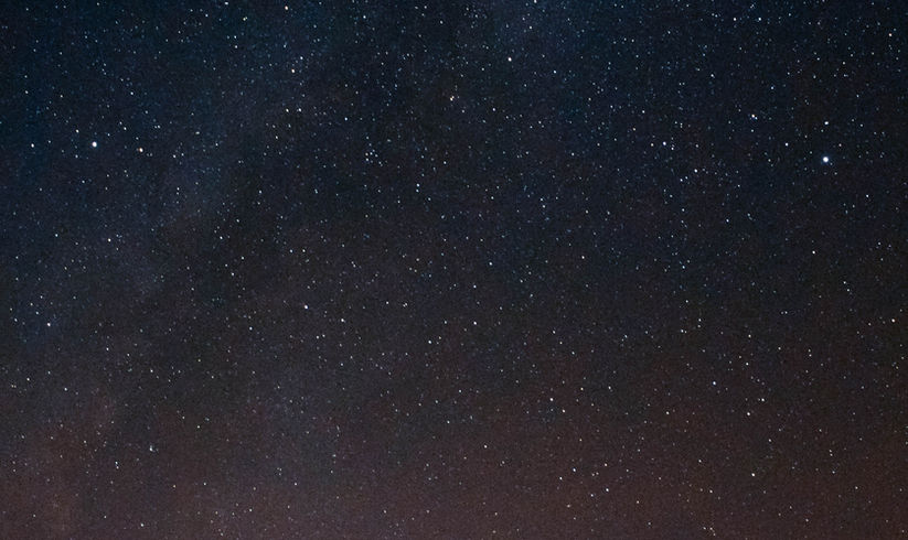 Groupe de visiteurs observant le ciel étoilé du Jura lors d’un pique-nique nocturne en pleine nature, avec vue panoramique et produits du terroir.