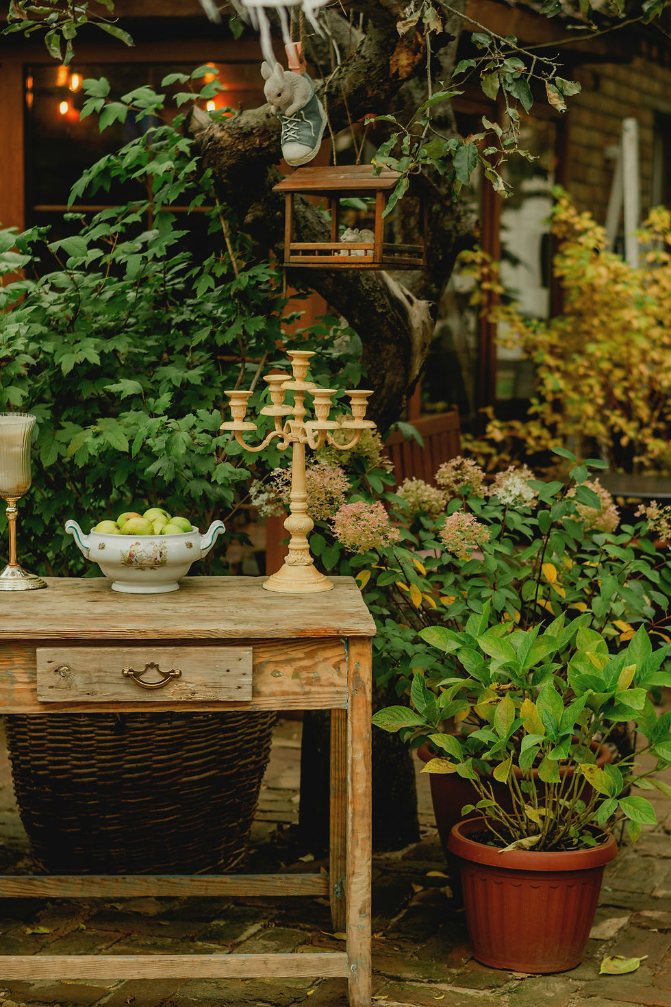 Outdoor setting with a rustic table and knick knacks amidst the plants. Boho vibe