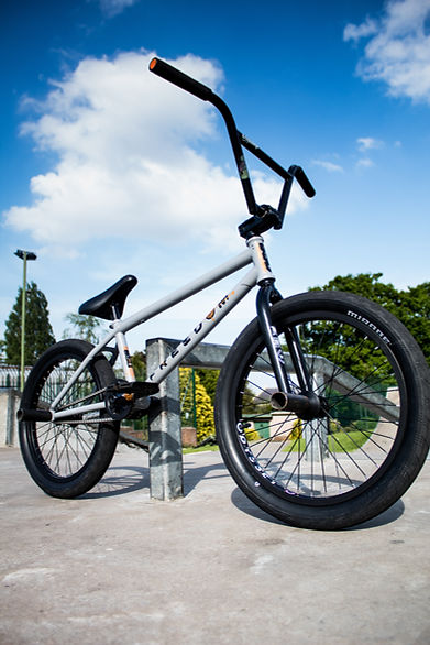 Silbernes BMX-Fahrrad mit schwarzem Lenker und Reifen vor blauem Himmel. Vagabundo