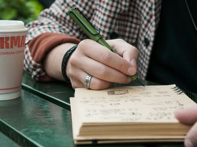 a girl writing in a notebook at a park