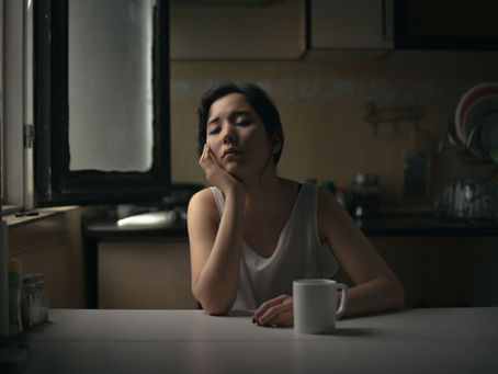A woman sitting quietly with a coffee cup in natural morning light — perimenopause fatigue is driven by mitochondrial energy loss, not poor sleep habits or lack of discipline
