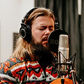 Adult guitar player singing in a recording studio