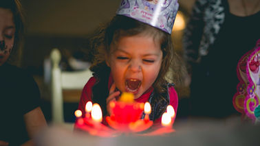 little girl blowing out candles of her birthday cake