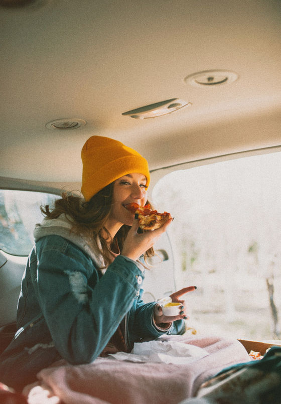 A young woman enjoying a slice of pizza mindfully.