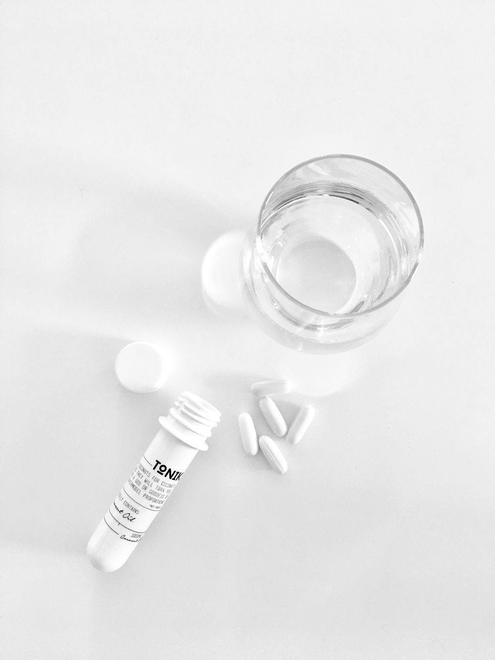 Prescription drugs on a white table with a glass of water
