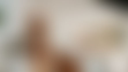 Modern kitchen with wooden cabinets, marble countertops, and hanging lights. Open book and bowl of apples on island. Sunlit dining area.