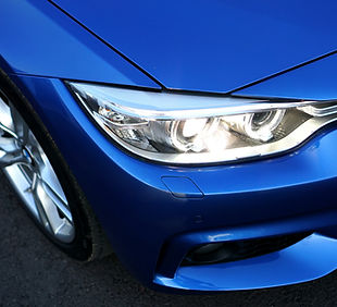 Close-up of a blue BMW headlight and front wheel.