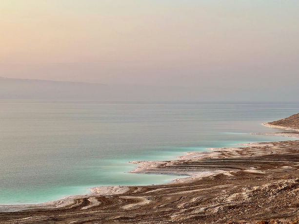 Panorama del Mar Morto in Giordania con acque turchesi, rive saline e paesaggio desertico all’orizzonte.