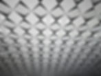 Modern ceiling of white diamond panels and recessed lights in a geometric pattern, creating a sleek, futuristic interior.