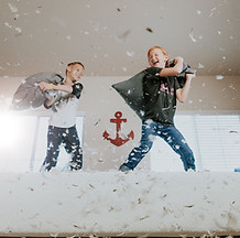 two children having a pillow fight on a bed