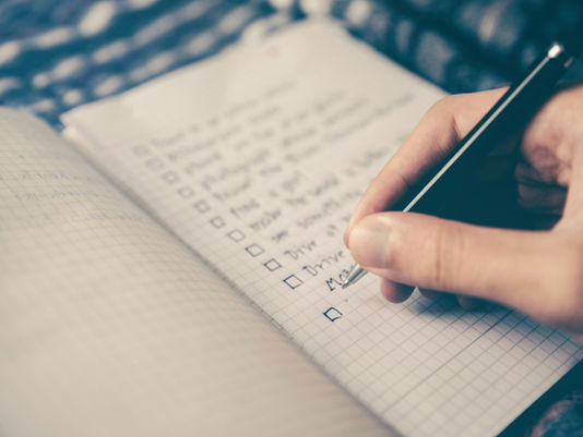 Hand writing a checklist with empty tick boxes in a notebook, illustrating checks before an MFHEA-approved change