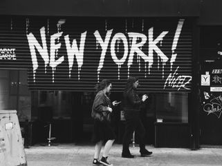A wall with the words "New York!" spraypainted on it