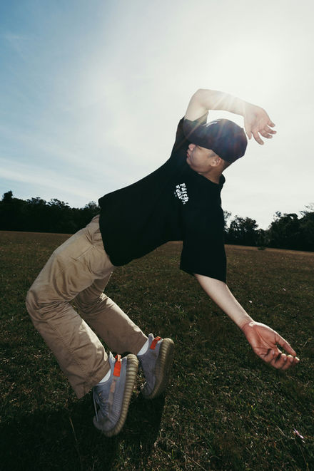 Golf trick performer jumping and reaching during an outdoor sports-themed performance on a grassy field.
