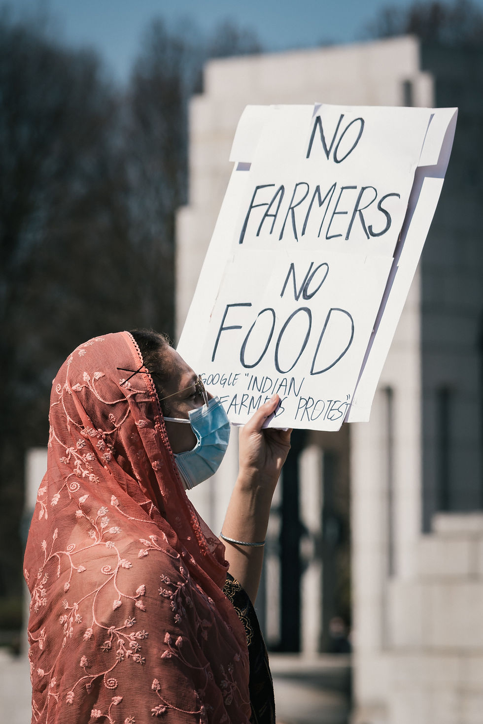 A woman holding up a white sign, "No farmers, no food", during a protest.