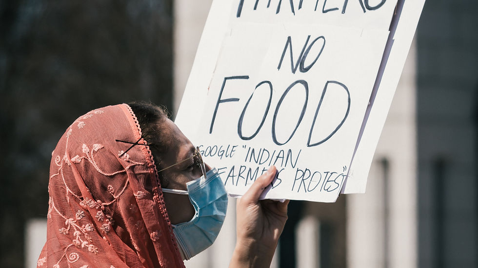 A woman holding up a white sign, "No farmers, no food", during a protest.