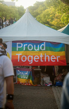 The pride flag with the words "Proud together" hangs in the entrance of a festival tent