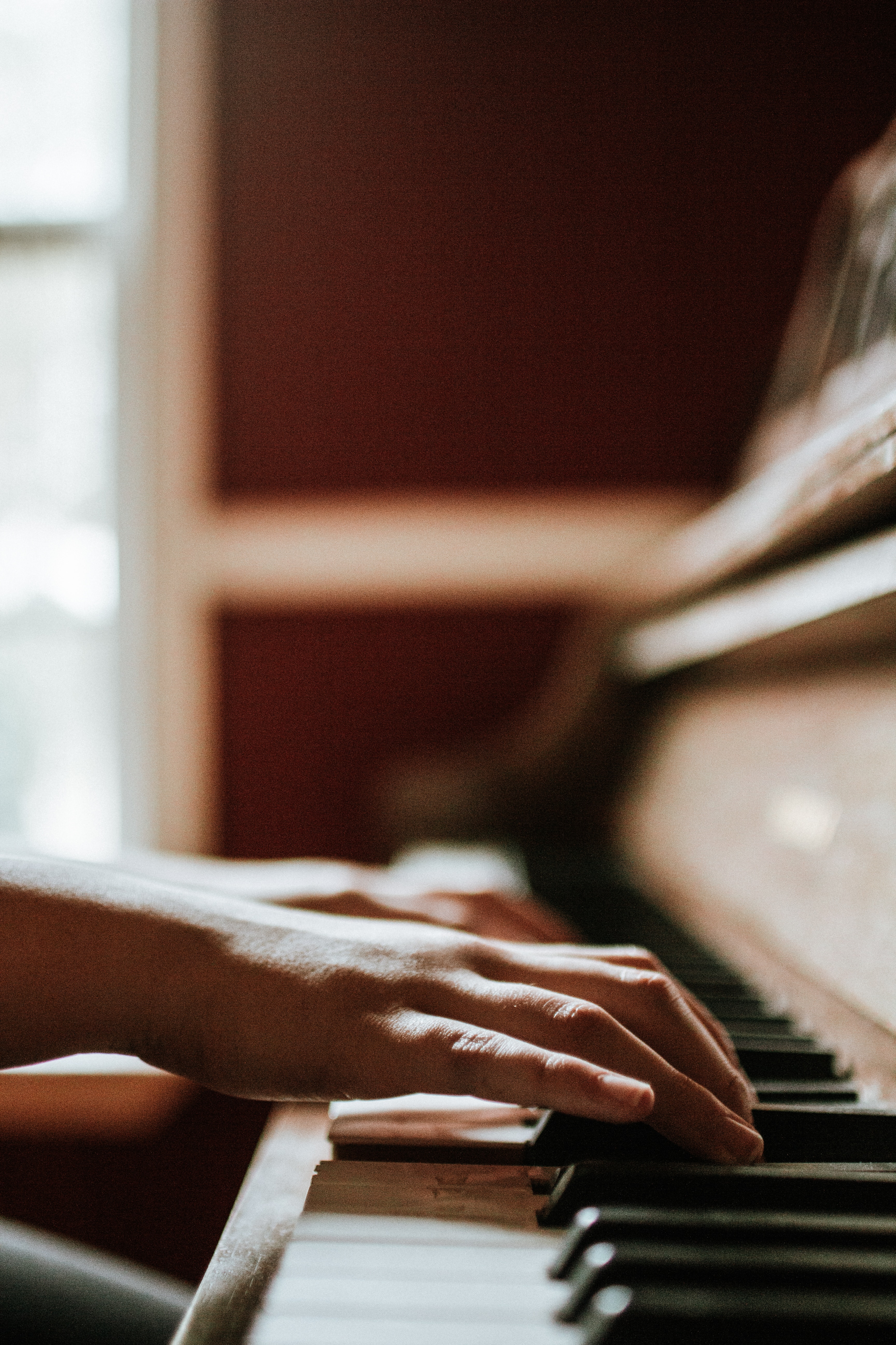 hands playing a piano keyboard, in profile