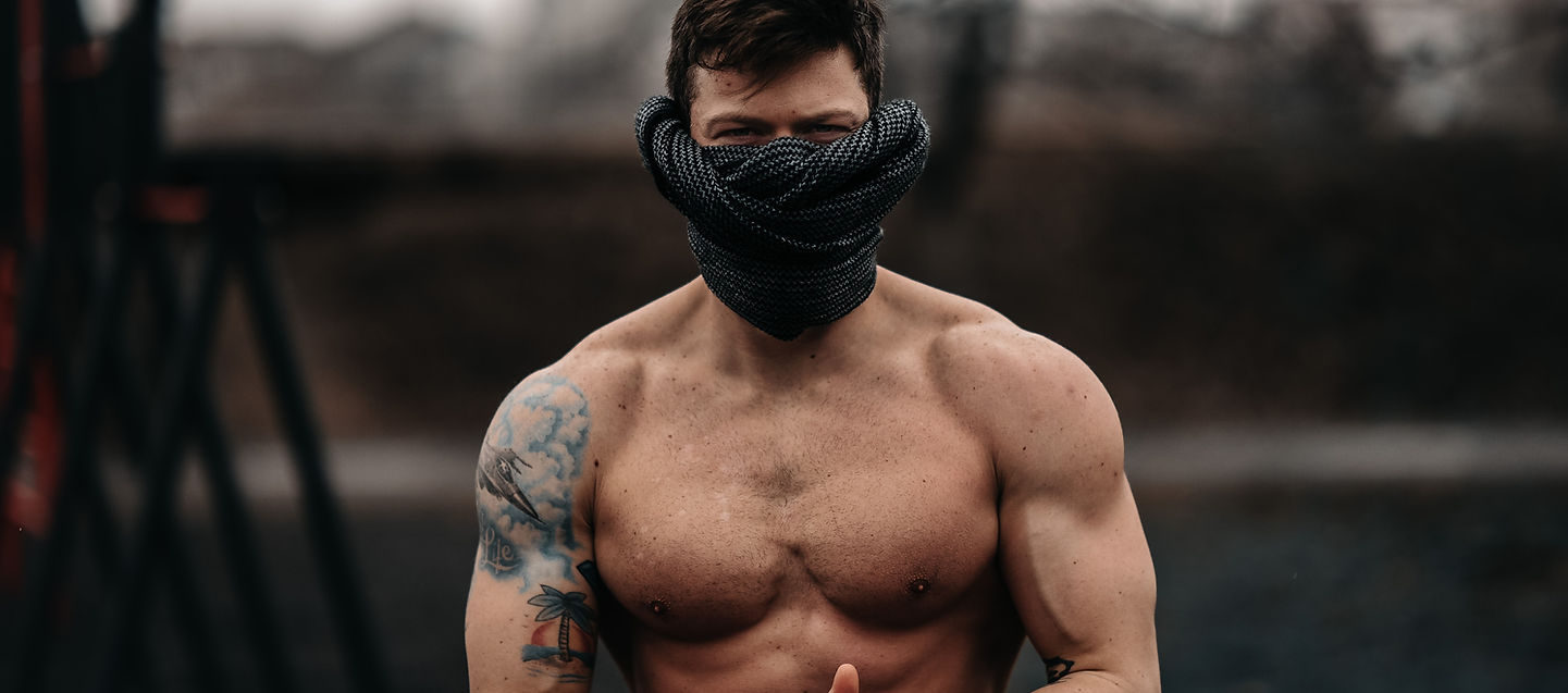 Strong man standing shirtless outdoors, symbolising raw masculinity.