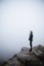 A confident individual standing atop a rock, symbolizing overcoming anxiety with determination and strength.