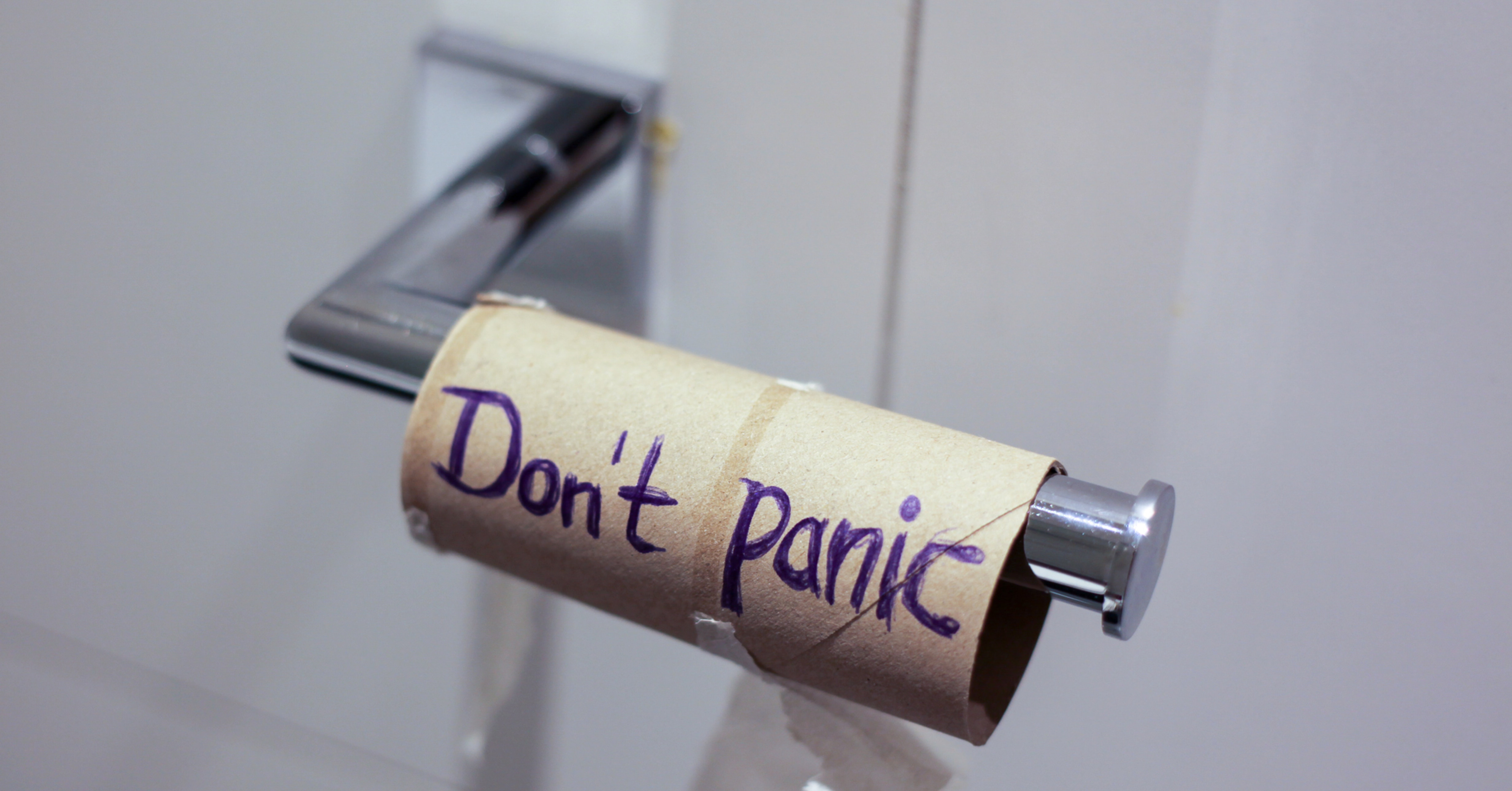 An empty cardboard toilet paper roll with "Don't panic" handwritten on it, representing late-night bathroom trips and nocturia frustration.