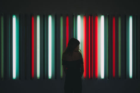 a woman stands in front of a wall of neon lights