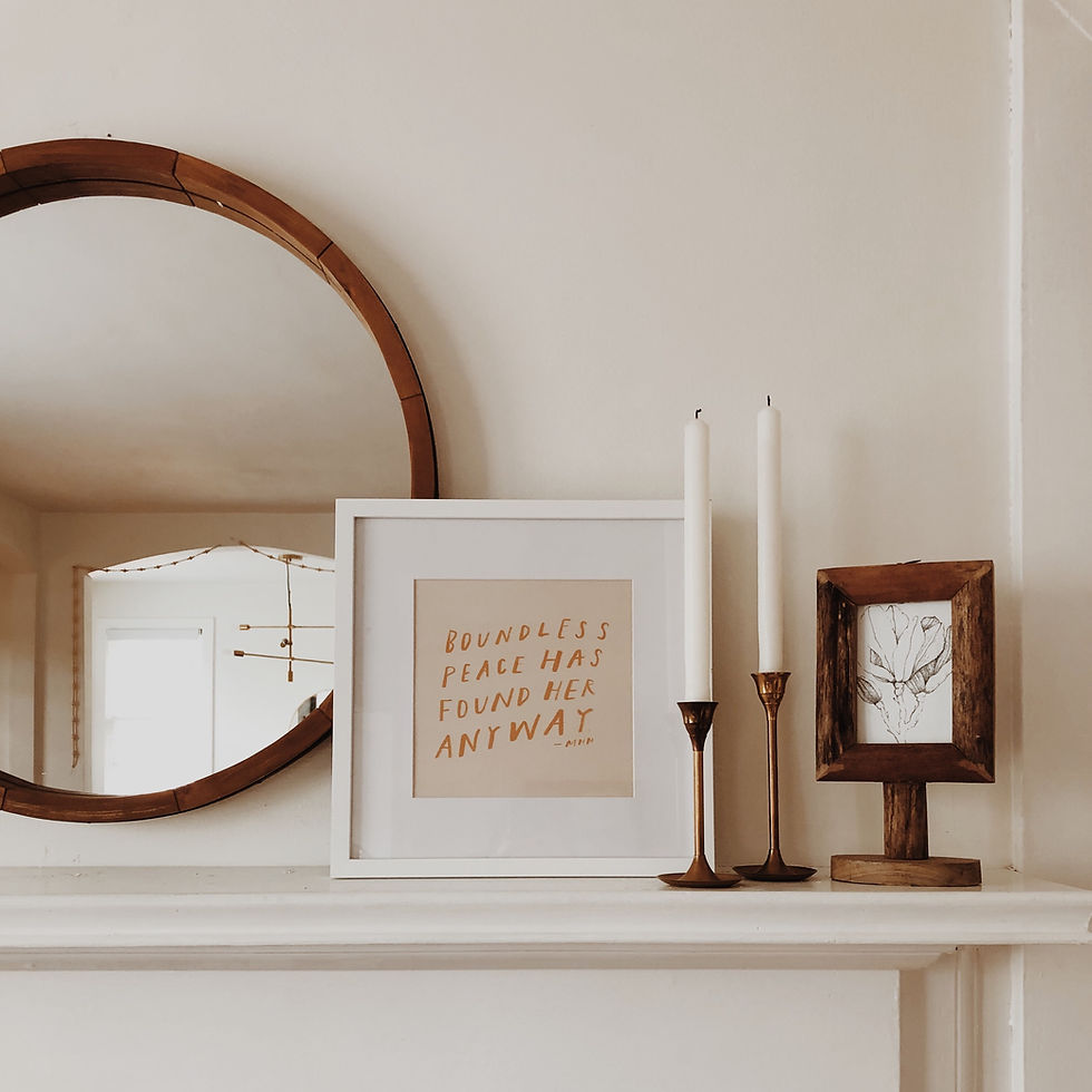 White mantle place with a white frame, round mirror and candles to signify the coming winter months