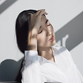 Woman with her eyes closed and hand on her forehead taking a deep breath