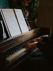 Image of a person playing the piano with only their hands visible while reading the sheet music.
