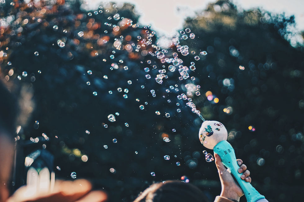 A bubble gun shooting buubles out into the sky, with trees behind it.