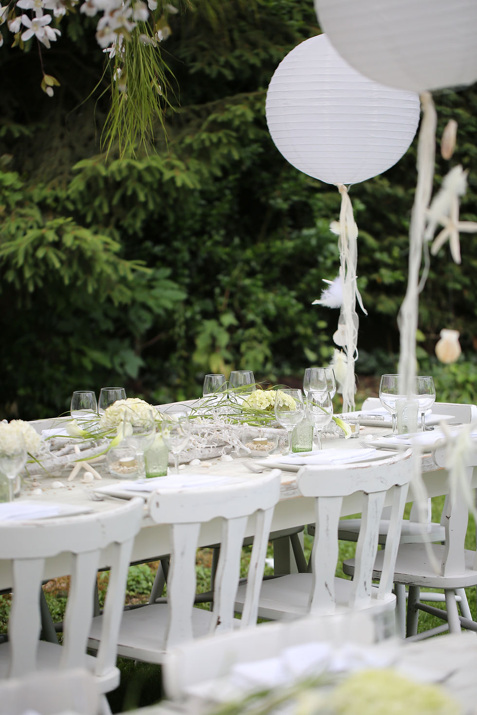 Table blanche décorée avec des fleurs blanches et des ballons, idéale pour une fête élégante ou une communion.