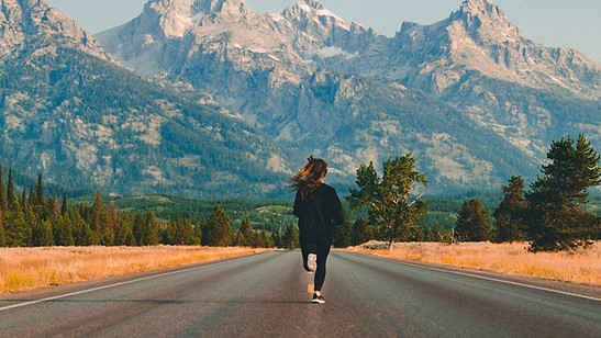 Girl running on road towards mountains