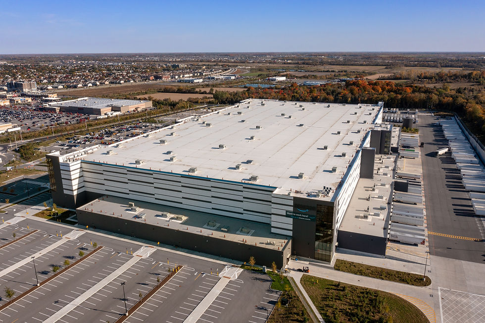 Aerial view of a large commercial warehouse facility with expansive rooftop and parking lot