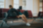 a person sleeps on a backpack in an airport terminal