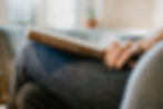 woman sitting with crossed legs with a parenting book on her lap