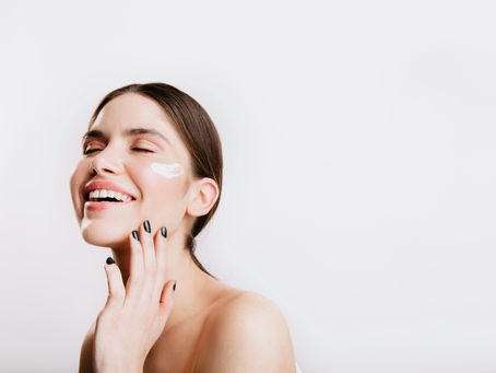 Woman with healthy, glowing skin applying skincare, smiling