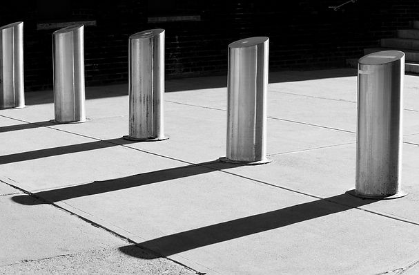 Row of sturdy cylindrical steel traffic control bollards providing security protection outside a building