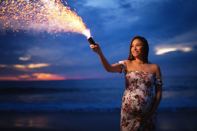 Expecting mother holding a sparkling firework during her maternity photoshoot in New York.