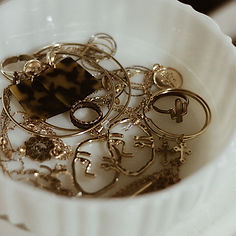 A white bowl filled with eclectic gold jewelry