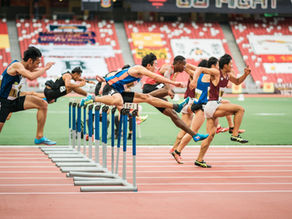 Athletes in a hurdle race on the track.