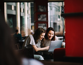 Two women looking at a laptop in a cafe