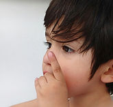 Junge hält Hand vor dem Mund